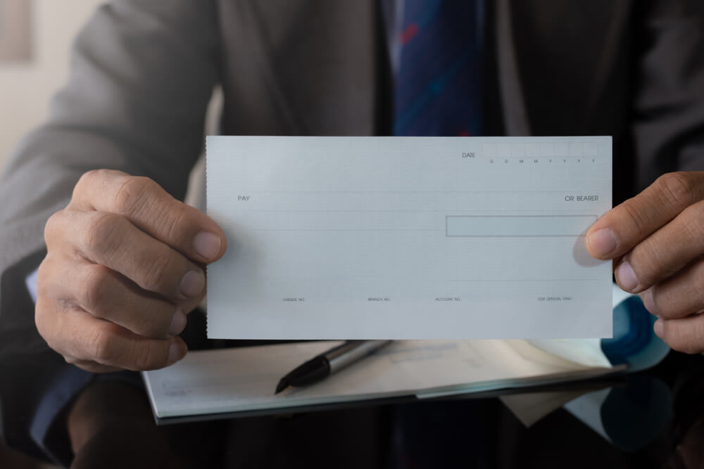 Businessman in Suit Hand Holding and Showing Blank Cheque