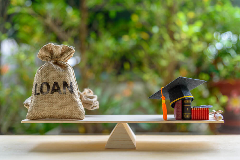 Mortarboard, Loan Bag on Balance Scale Student Loan Disbursement Concept